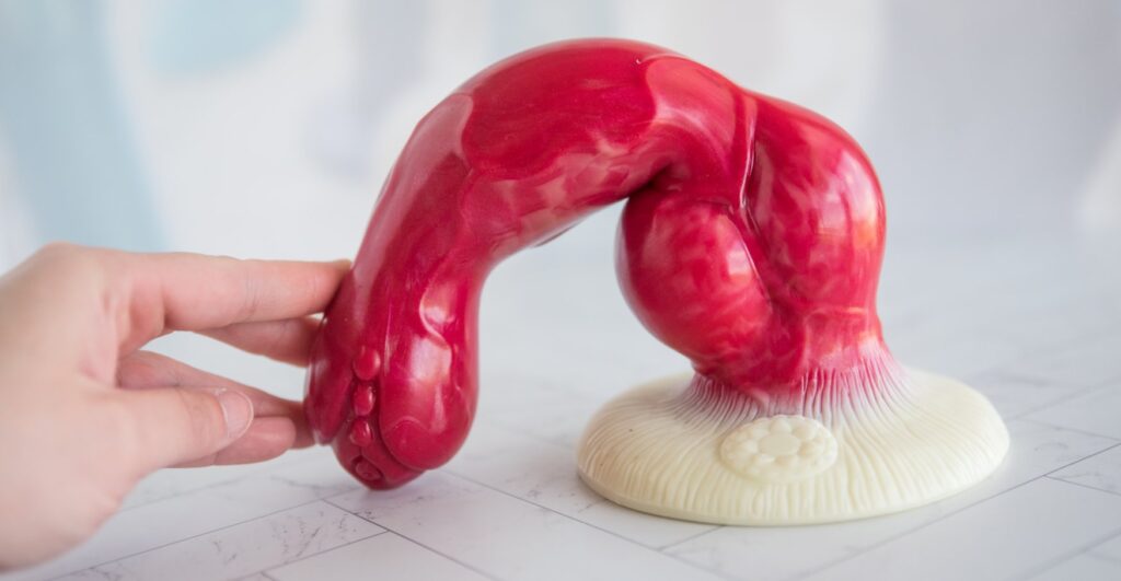 My fingers touch the tip of the dildo while the base is suction cupped onto the base underneath it. I bend it in half, touching the tip of the dildo into the floor next to the base. The knot isn't very flexible or bendable but the shaft itself will bend.