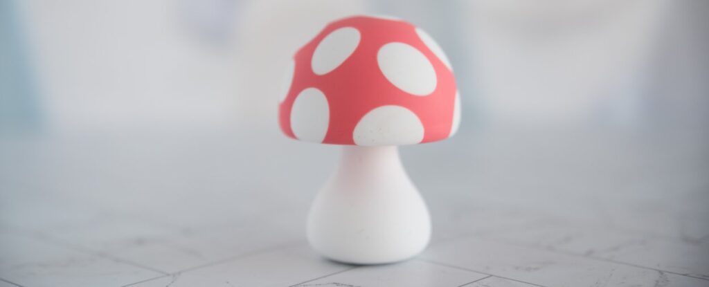 The Mushroom Vibez sex toy from Woo More Play sitting in front of a plain background. It sits upright with no help or assistance, looking like a really cute mushroom knick knack.
