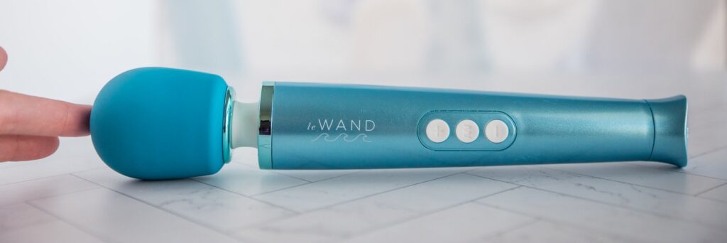 A full-frontal shot of the Dive just sitting on the ground. It has three buttons on it with a gorgeous blue coloration. There's a slight flare at the base for easier handling of its slick plastic handle. For my Le Wand Dive review.