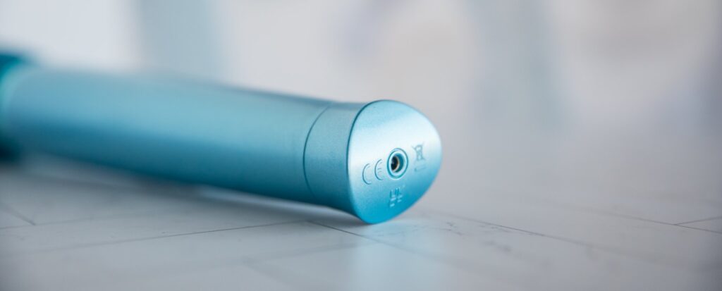 Close-up on the bottom of the wand. This charging port hole is open at all times, but it has a waterproof design to prevent water from ruining the toy if it gets within this hole. For my Le Wand Dive review.