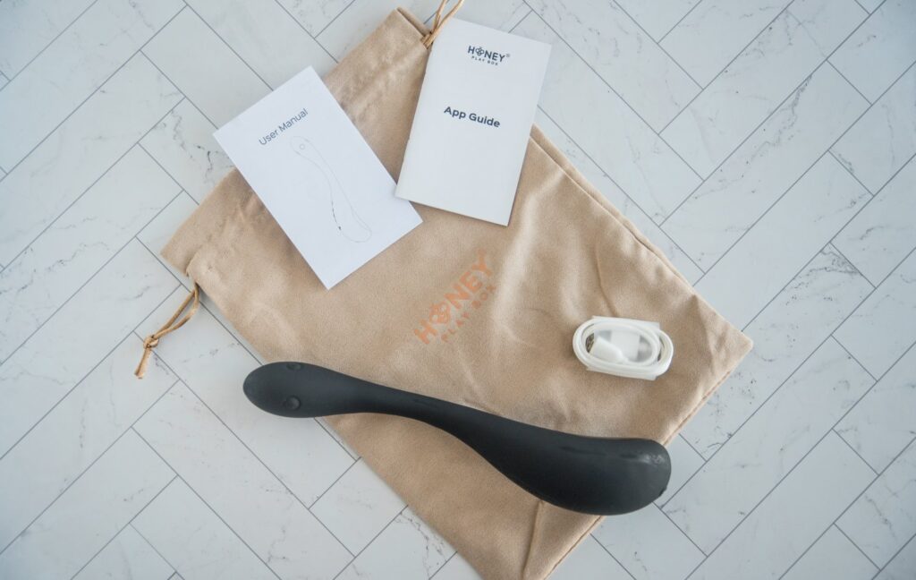 Everything included with the AIRA. There's a suede drawstring beige bag, the charging cable, an app guide, the user manual, and the toy itself. For my Honey Play Box AIRA review.