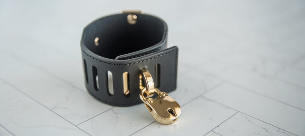 The cuff shown with the fastening post pushed through the hole to fasten the cuff shut. There is a lock in the fastening post, showing how these cuffs lock onto someone.