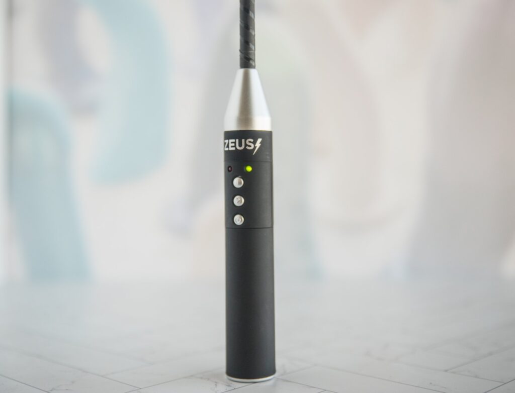 The Zeus shocking riding crop is turned on and live, showing the bright green light that lets you know. For my Dr. Sado e-Stim Crop review.