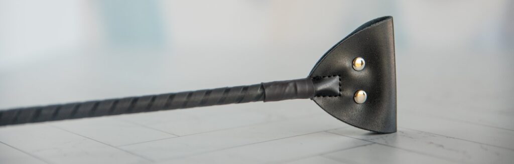 Close-up on the tip of the crop. It has two conductive metal contact points at the tip. For my Dr. Sado e-Stim Crop review.