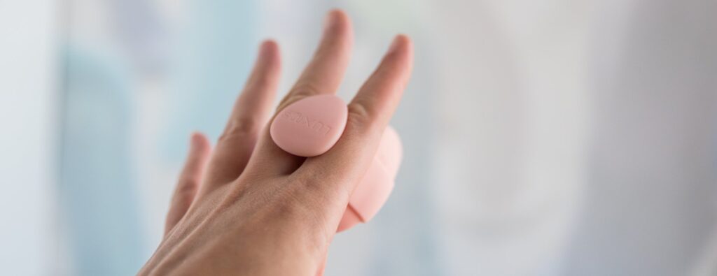 The LuxHer vibrator is in the Finger Grip holster. The Finger Grip is tucked in-between my pointer and middle fingers so it holds itself there and doesn't need to be held between my fingers.