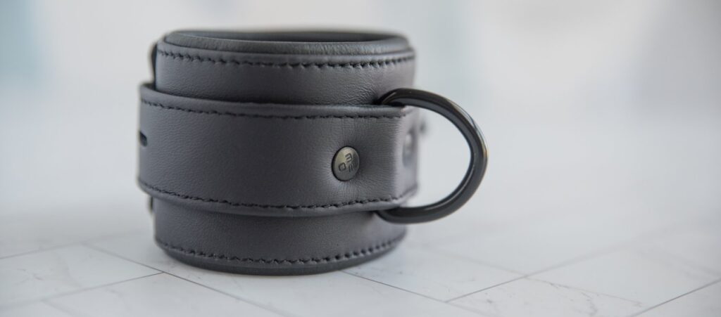 Close-up of the D-ring, showcasing how it is riveted around the ring, allowing the D-ring to rotate within its confined spot. For my MEO.de Lockable Chicago Neoprene Restraints review.