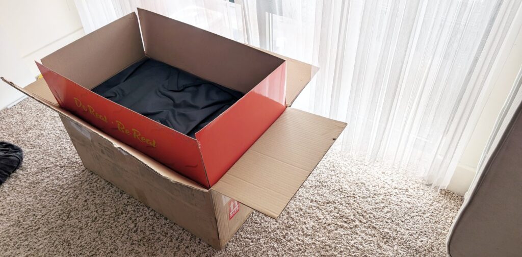 The packaging the Tantaly Hannah ships in. There's the brown outermost boring box, the interior orange retail box, and the black bag for long-term storage.