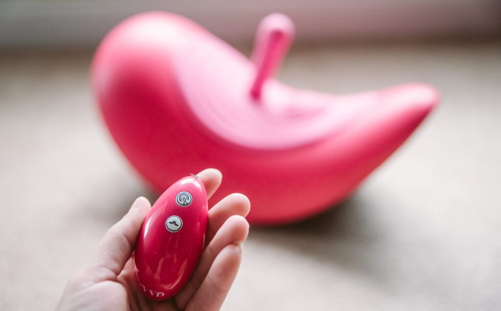 My hand holds the physical remote for the Rider Desire. It is a small, egg-shaped remote with two buttons on it.