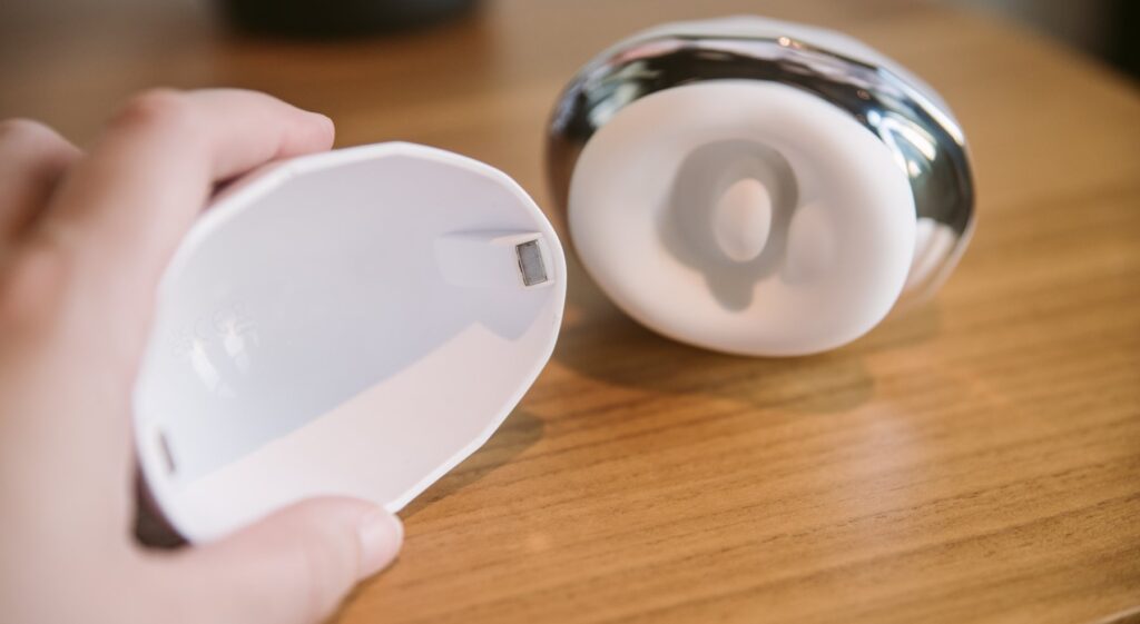 My hand holds the lid for the Cloud Kiss, the camera focused on the magnets that are built into the sides of the vibrator's lid. The magnets easily attach the lid onto the Cloud Kiss itself.