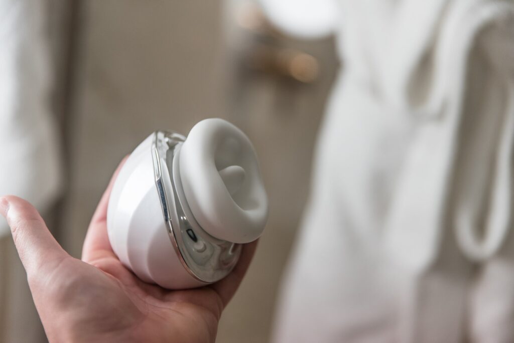 My hand holds the vibrator. It takes up most of my palm, and it is surprisingly thick, protruding away from my palm. For my Joylume Cloud Kiss review.