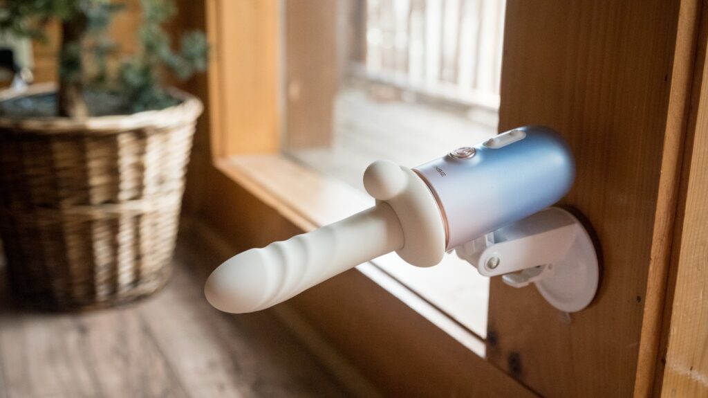 The clitoral attachment is shown attached onto the machine, slid on a dildo, showing how it can offer clitoral pleasure. For my Lovense Spinel review.