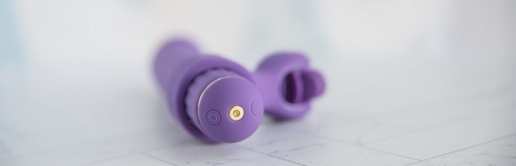 Close-up on the base of the toy. There are two buttons on the base alongside the magnetic charging port. For my AVIDLOVE PLAY Four-Attachment Rabbit Vibrator review.