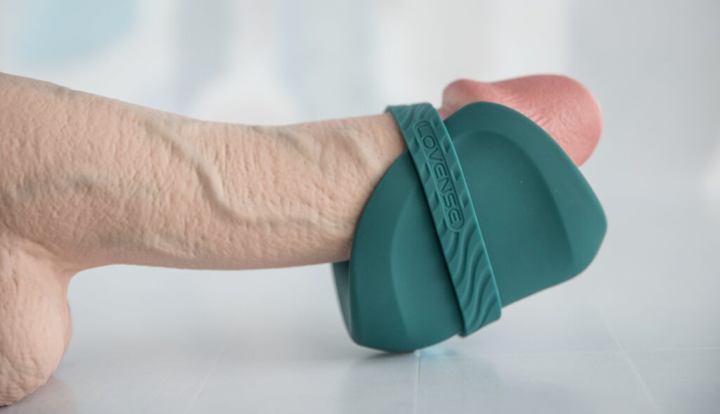 Side view of the Gush 2 wrapped around the tip of the dildo. The hands-free band is wrapped around the Gush 2 and the dildo's shaft, showing how the band works. For my Lovense Gush 2 review.
