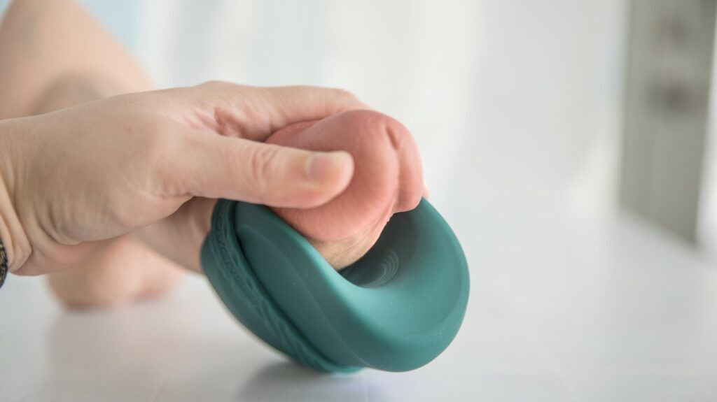 Showing the thrumming area on the center of the Gush 2 and how it easily lines up with the frenulum of a shaft. A dildo showcases how it would fit with a penis.