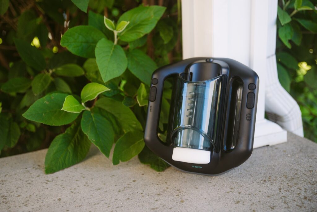 The Jetpack sits out on the cement in front of a green tree. It looks futuristic, yet welcoming, outdoors. For my SVAKOM Jetpack review.