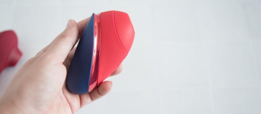 My hand holds the Womanizer Next Liberty. The tip of the toy is built into the size of the toy itself, and it doesn't really "protrude".
