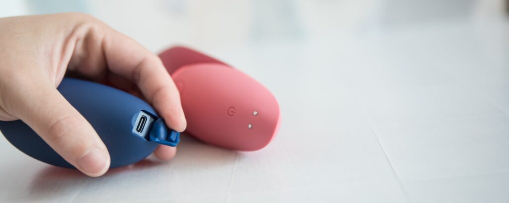 The base of both toys, showcasing their difference in charging styles. The Womanizer Next has a two-pronged magnetic charging system. The Womanizer Next Liberty's charging port "door" is open and showing the interior USB-C port. For my Womanizer Next Liberty vs Womanizer Next comparison