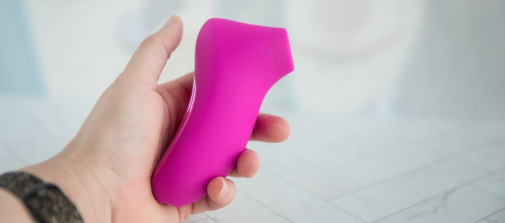 My hand holds the toy at a sideways angle. It has a slightly protruding tip. For my AVIDLOVE PLAY Ergonomic Max Suction Clitoral Vibrator review.