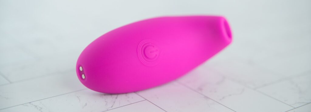 Close-up on the handle, showcasing the single power button and the two magnetic charging prongs at the base.